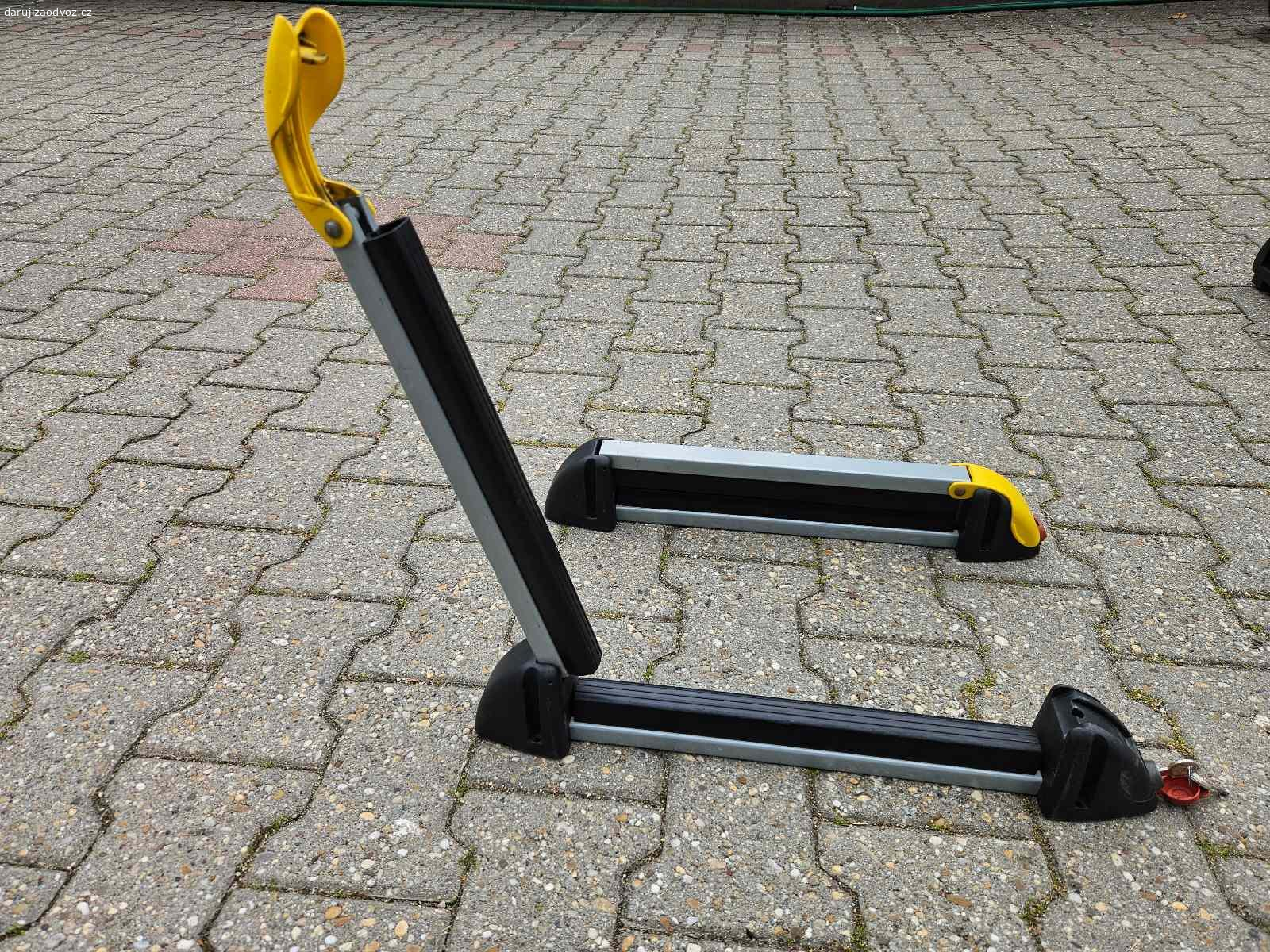 Držák lyží / snowboardů na střešní nosič. Celková délka je 53 cm, vnitřní délka pro uložení lyží / snowboardů je 37 cm.