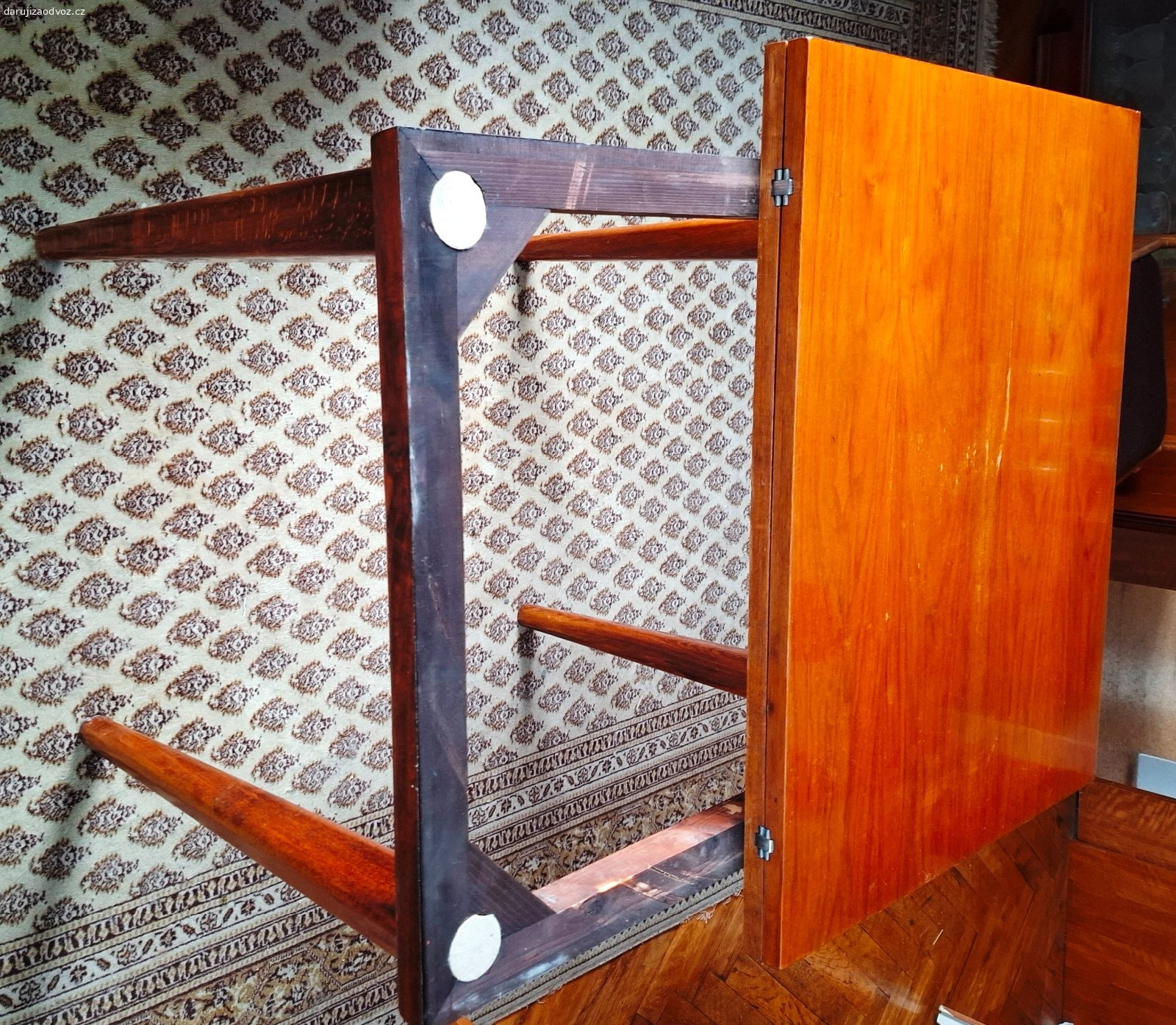 Jídelní rozkládací stůl (ořech) + 4 židle. Originální, velmi zachovalou retro sadu dřevěného nábytku z období československého designu (přelom 50. a 60. let, Brusel). Set se skládá z rozkládacího stolu a 4 designových židlí. Na spodní straně stolu je kompletně dochovaný původní papírový štítek výrobce.

Výrobce: ČESKÝ NÁBYTEK, n. p., provozovna Liberec (Sdružení nábytkářského průmyslu Brno)
Model/Výrobek: 42-341
Materiál a provedení: Kvalitní ořech, lakovaný povrch s krásnou texturou dřeva.

Židle: 4 kusy s elegantně tvarovaným opěradlem. Tmavě hnědé čalounění s jemným svislým proužkem je čisté, neprosezené a ve velmi zachovalém stavu.

Stav: Vše je v původním stavu, dřevo i lak nesou pouze minimální známky šetrného používání. Žádné hluboké škrábance nebo poškození. Rozkládací mechanizmus stolu (kovové panty) je plně funkční a pevný.

Rozměry stolu: (výška x šířka x délka):  75 / 66 / 115 cm (ve složeném stavu)

Nádherný designový set, který okamžitě zapadne do moderního i retro interiéru.

Odběr: Pouze osobní odběr ve Zlíně