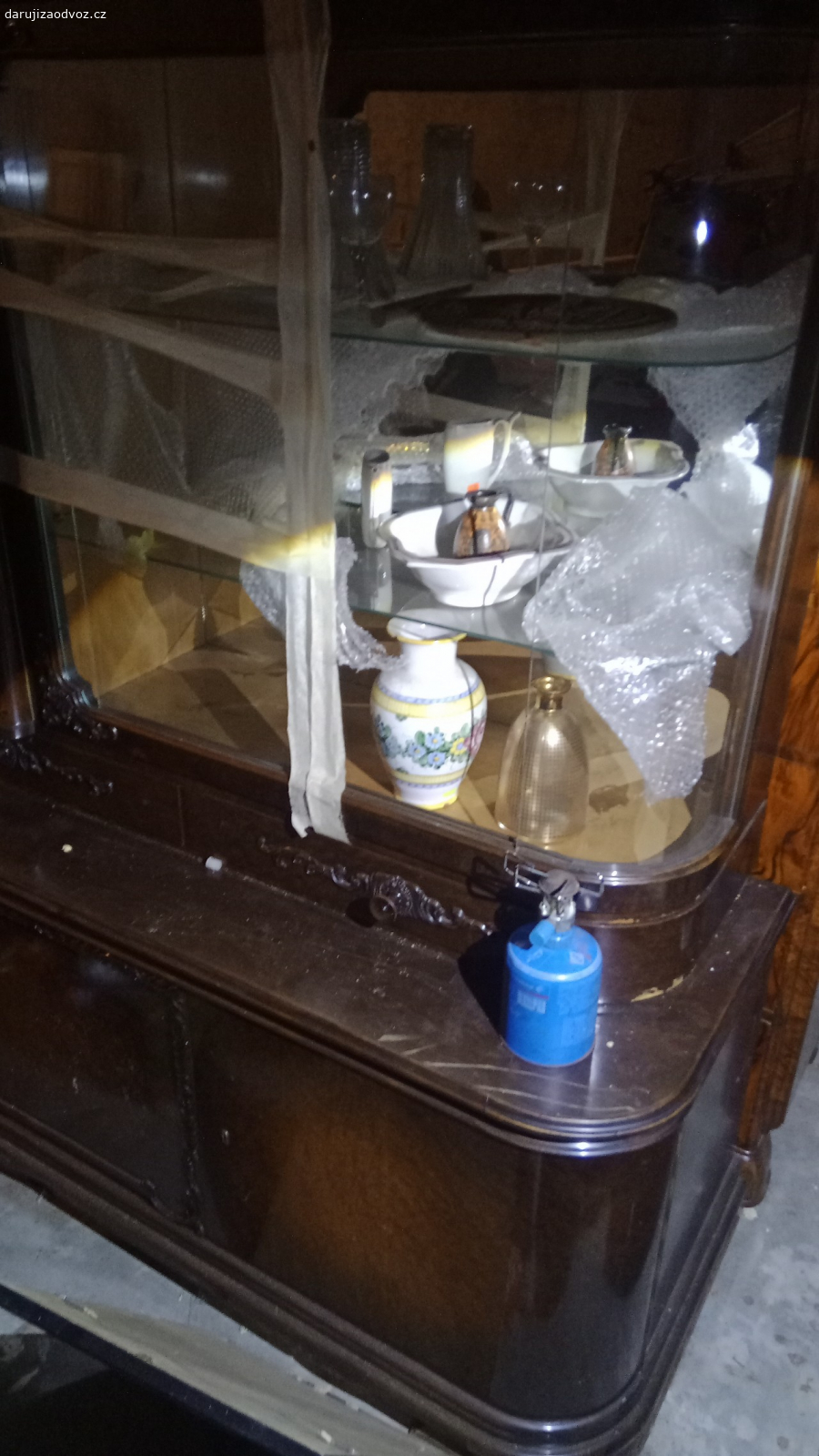 Krásná vitrína prvorepubliková. Má (nejspíš) řezbované detaily.
roh vitríny je z oblého skla.
Pěkná práce. 
To není IKEA, to Vás přežije ??
Za odvoz ?