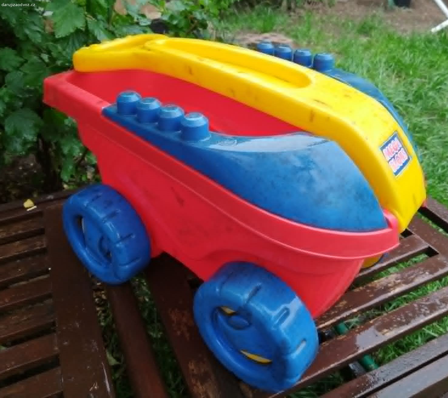 Plastový tahací vozík Mega Bloks – bez kostek. Daruji (ovoce pro děti potěší, není podmínkou) dětský tahací vozík značky Mega Bloks (Mattel). Vozík je používaný, nese známky hraní viditelné na fotkách, ale je plně funkční, robustní, plast nikde nepraskl, poslední dobou byl na zahradě. Má sklápěcí žluté madlo a modré bočnice s výstupky, na které lze kostky přímo stavět. Ideální jako úložný box na hračky nebo na převážení venku. Předám Praha 10-Strašnice, samostatně BEZ stavebních kostek.
