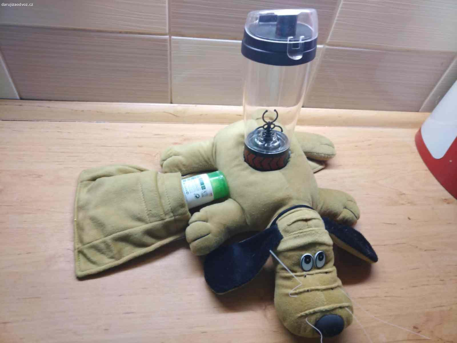 Retro pejsek na pohovku – držák na ovladače a pití. Daruji (třeba ovoce pro děti potěší - není podmínkou) textilní držák / organizér na pohovku nebo křeslo na opěradlo, ve tvaru pejska. 
Praktický i dekorativní doplněk k televizi, třeba na ovladače.
Pejsek je uvnitř vyplněn zátěží, díky které stabilně drží na okraji pohovky nebo křesla bez nutnosti uchycení.
Uprostřed má kruhový otvor na láhev nebo sklenici a po stranách kapsy na uložení až dvou dálkových ovladačů nebo drobností - viz  foto.
Předám bez obsahu ( lahev - šejkr už není) v Praze 10-Strašnice.