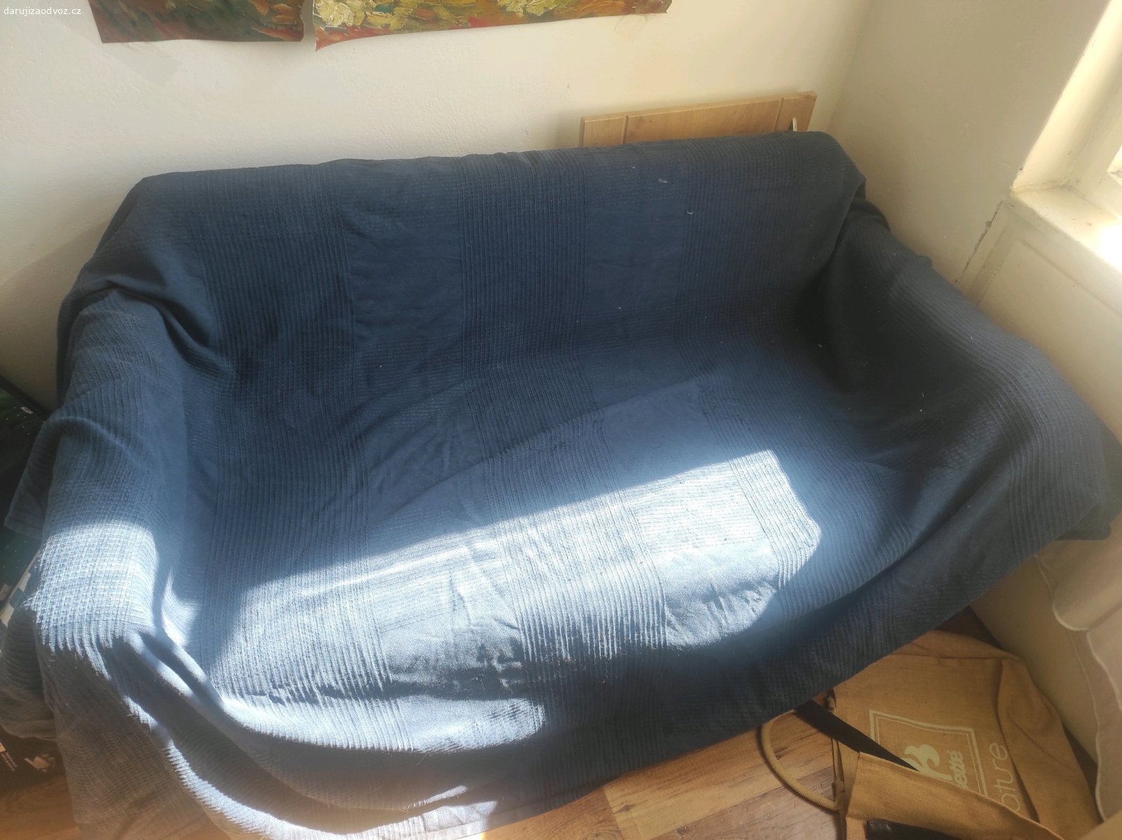 Rozložná pohovka s přehozem. Starší, méně používaná.